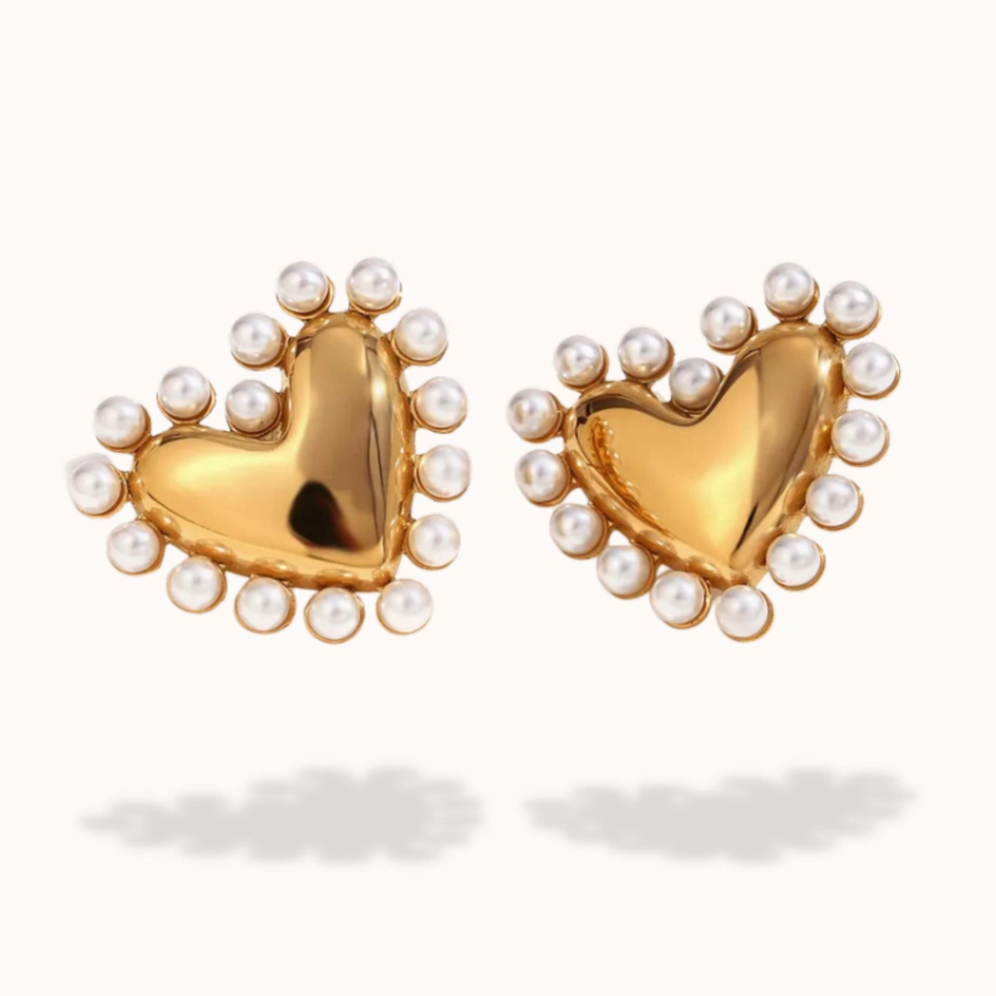 Gold heart-shaped earrings with pearl accents on a white background