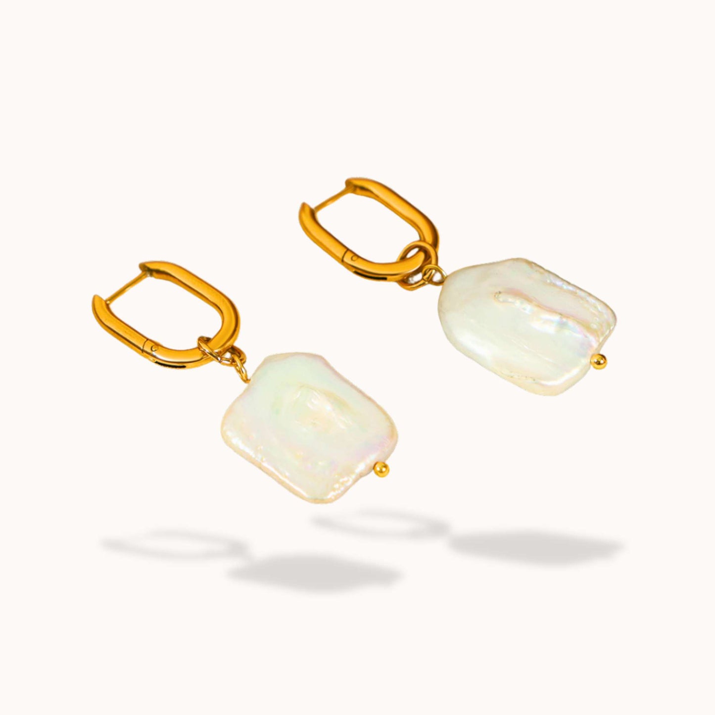 Gold earrings with dangling Fresh water pearl on a white background
