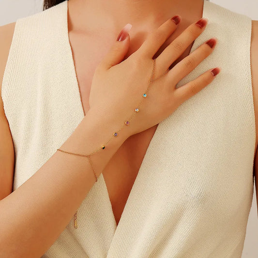 Close-up of a hand wearing a delicate bracelet with small stones, against a neutral background.