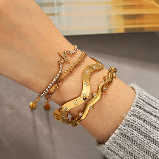 Gold bracelets on a wrist with a neutral background