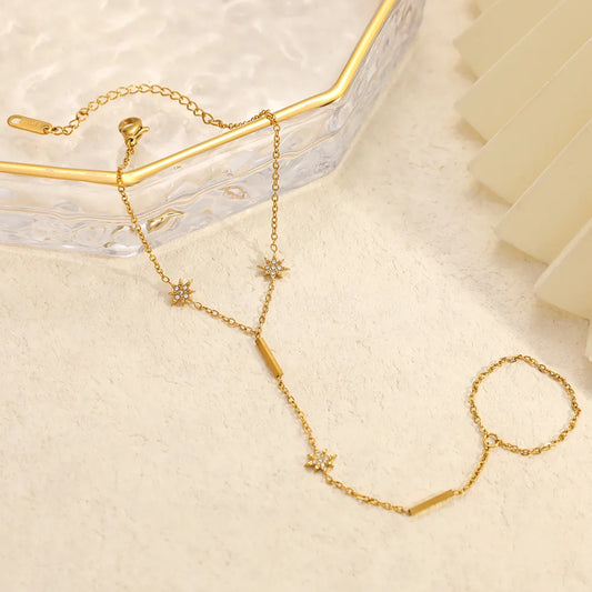 Gold necklace with star-shaped pendants on a light beige surface