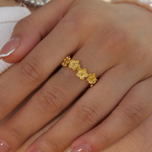 Gold floral ring on a person's finger