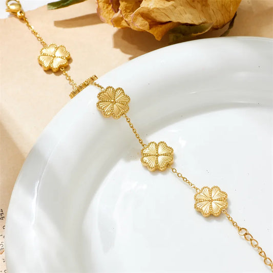 Gold necklace with floral designs on a white plate with a beige background