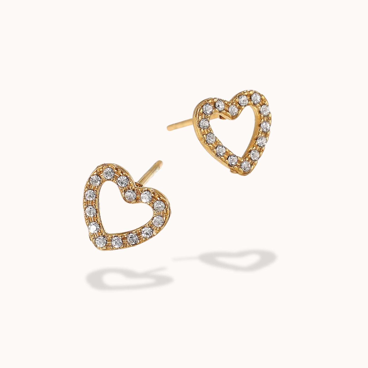 Heart-shaped gold earrings with clear gemstones on a white background