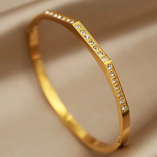 Gold bracelet with small diamonds on a beige background