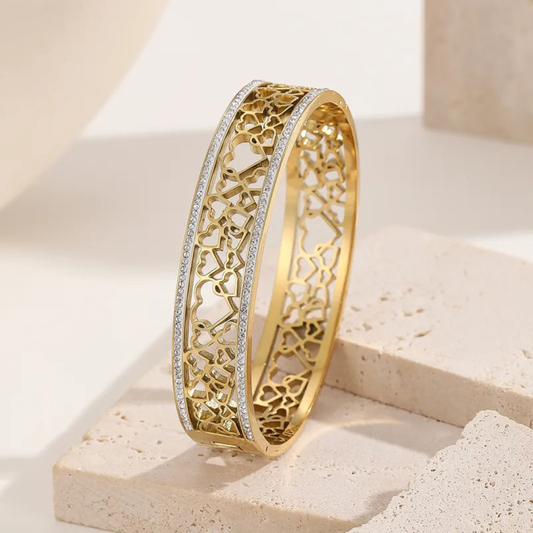 Gold bracelet with intricate design on a light stone surface