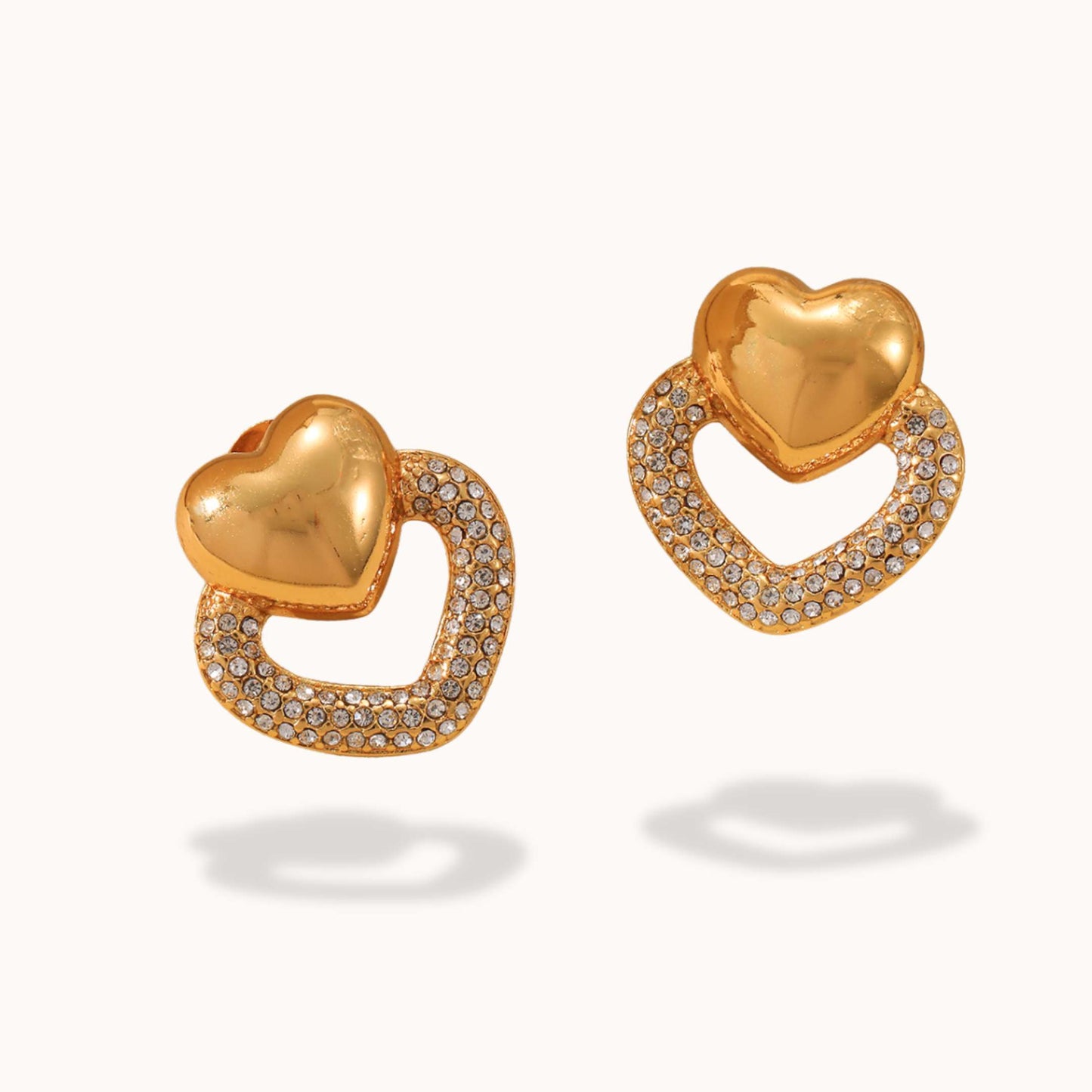 Gold heart-shaped earrings with diamond accents on a white background
