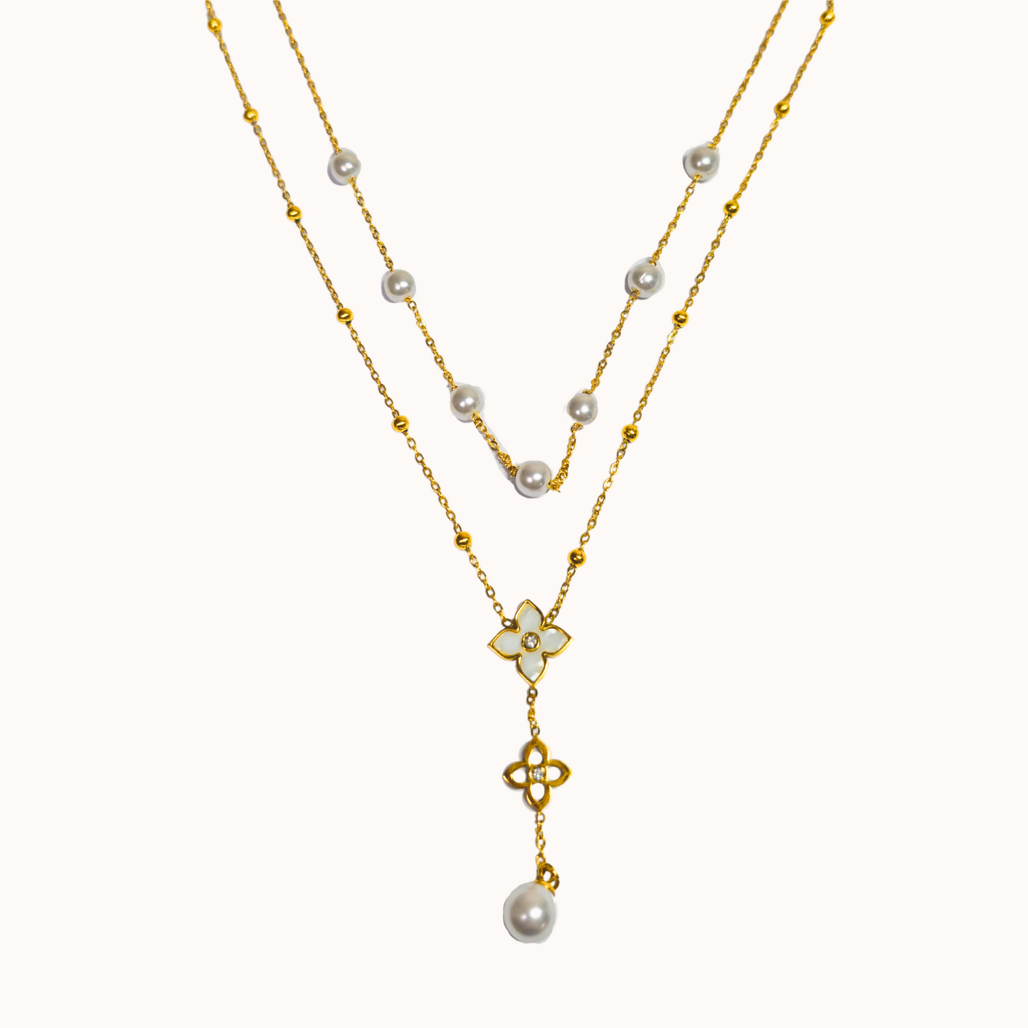 Two-layered necklace with pearls and a floral pendant on a white background