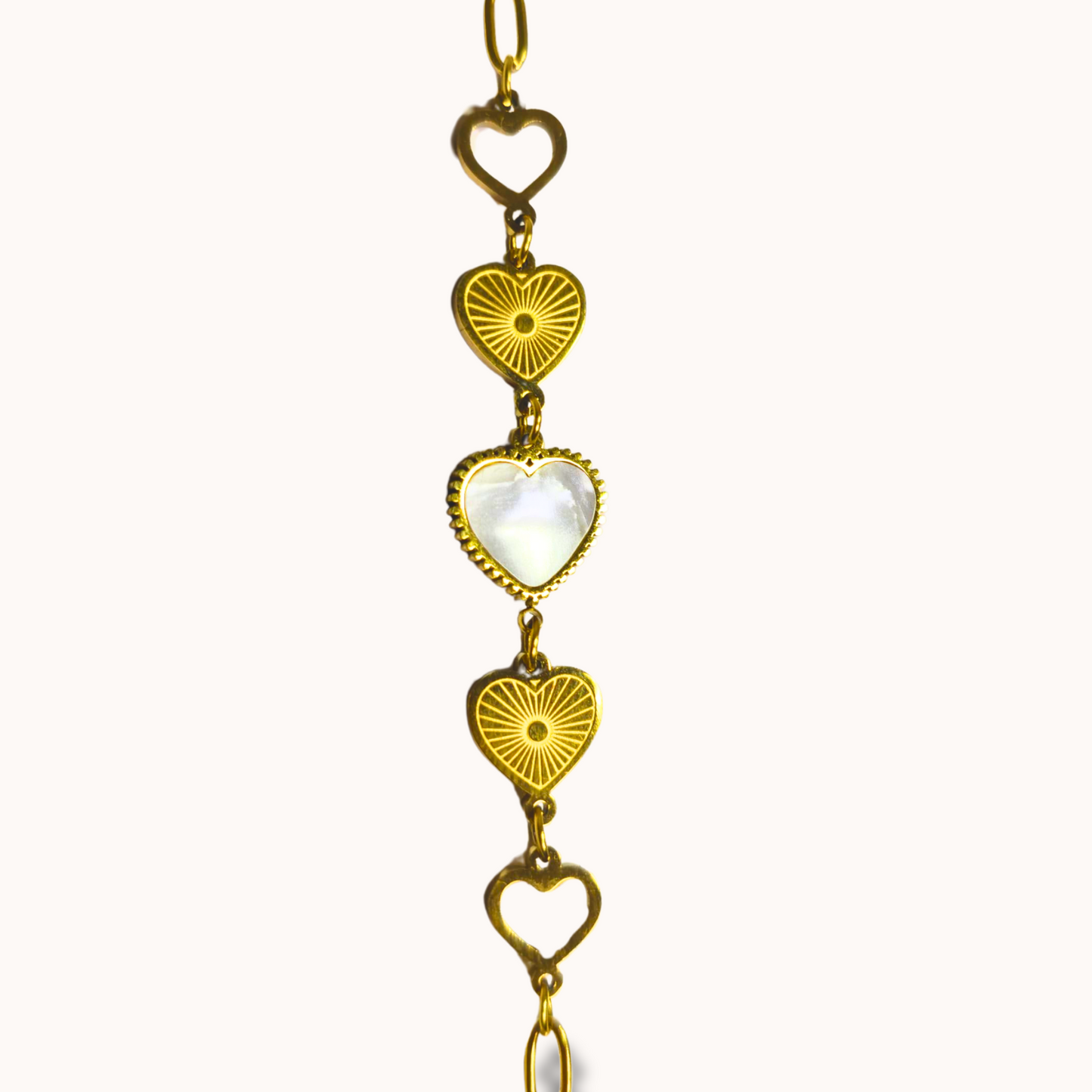 Gold necklace with heart and sunburst designs on a white background