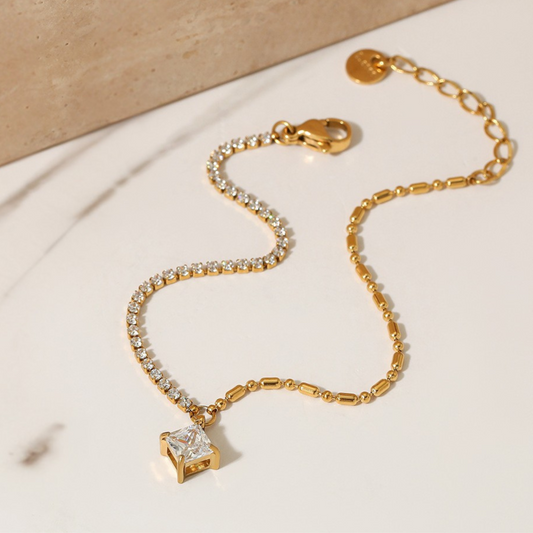 Gold bracelet with diamond charm on a beige background