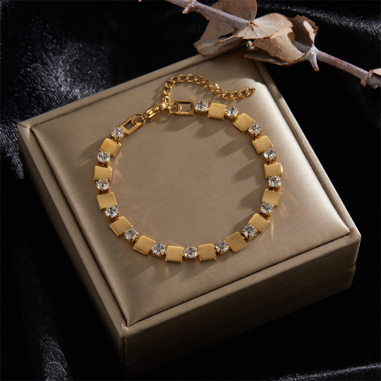 Gold bracelet with diamond accents on a beige jewelry box against a dark background