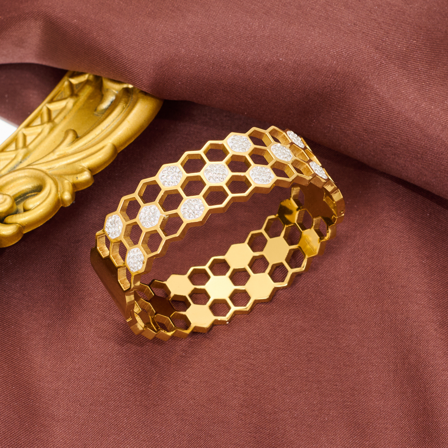 Gold bracelet with honeycomb pattern on a brown fabric background