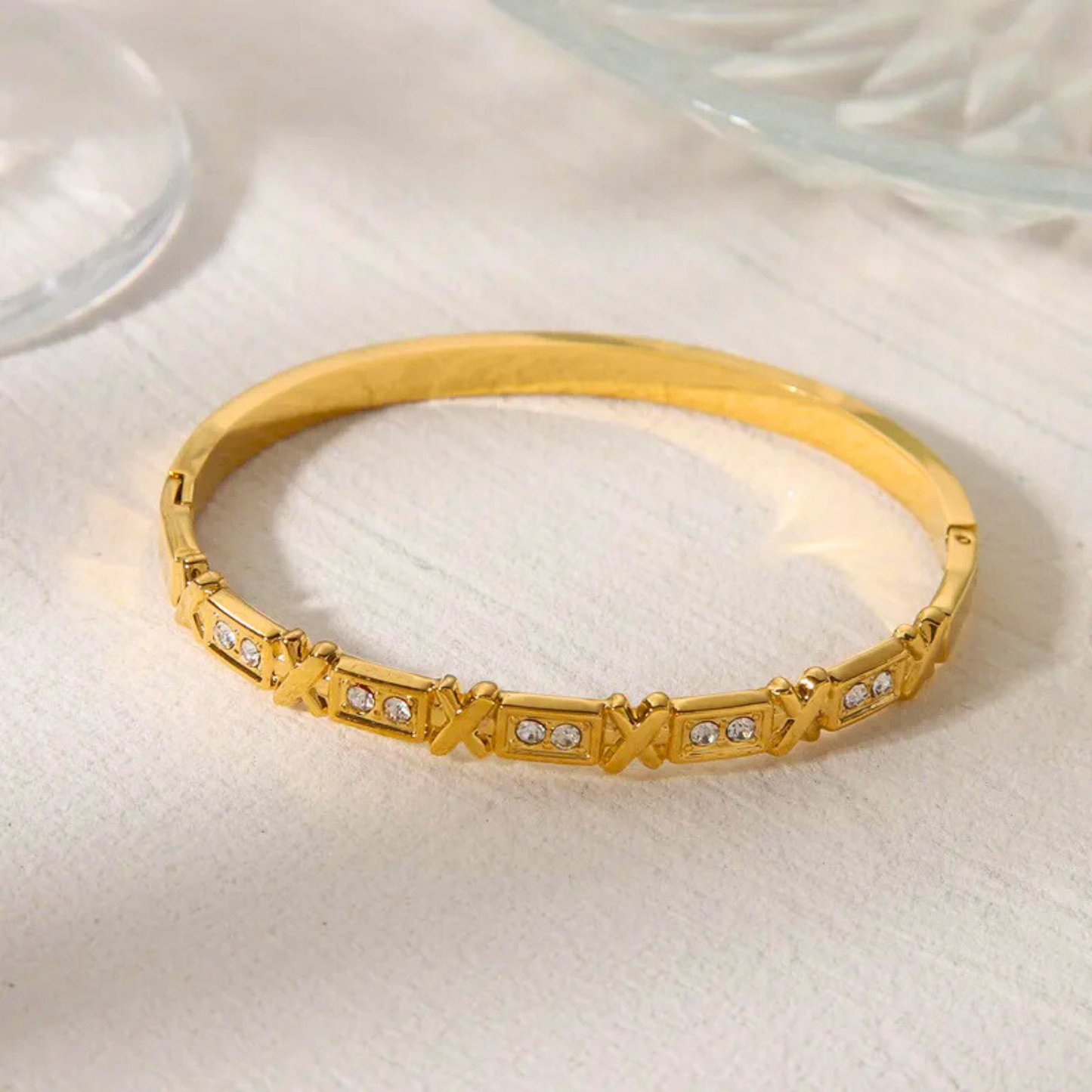 Gold bracelet with diamond accents on a light background