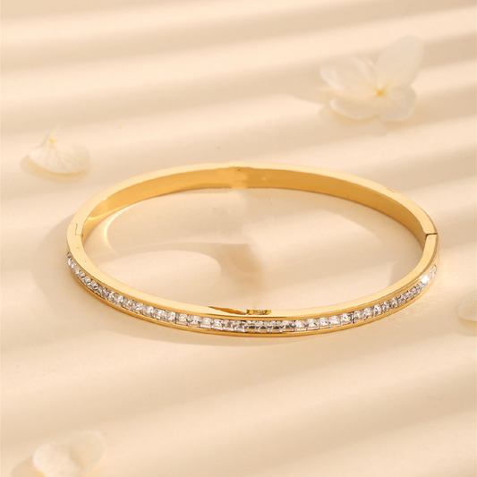Gold bracelet with diamonds on a beige background