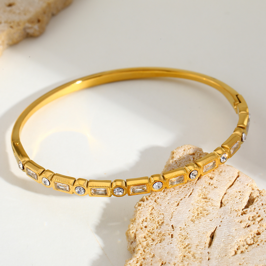 Gold bracelet with gemstones on a light background