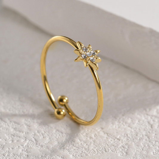 Gold ring with star-shaped design on a textured white surface