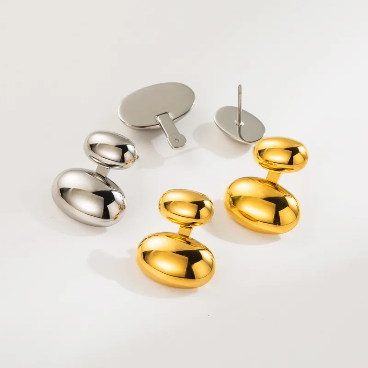 Pair of gold and silver earrings on a light gray background