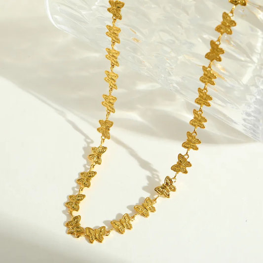 Gold butterfly necklace on a white fabric background
