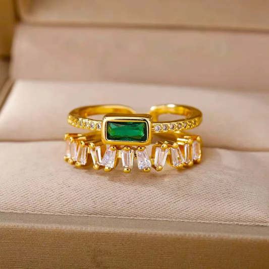 Gold ring with emerald and baguette diamonds on a beige fabric background