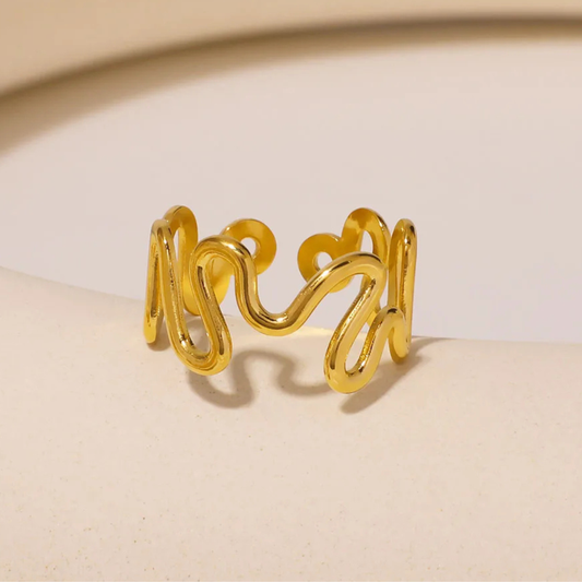 Gold ring with wavy design on a beige background