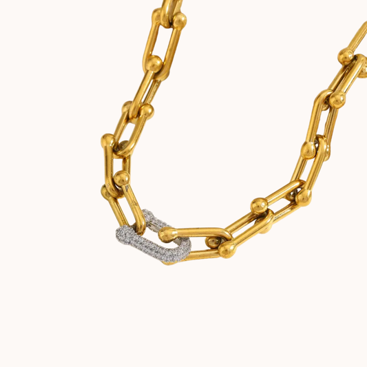 Gold chain necklace with a diamond-encrusted heart pendant on a white background