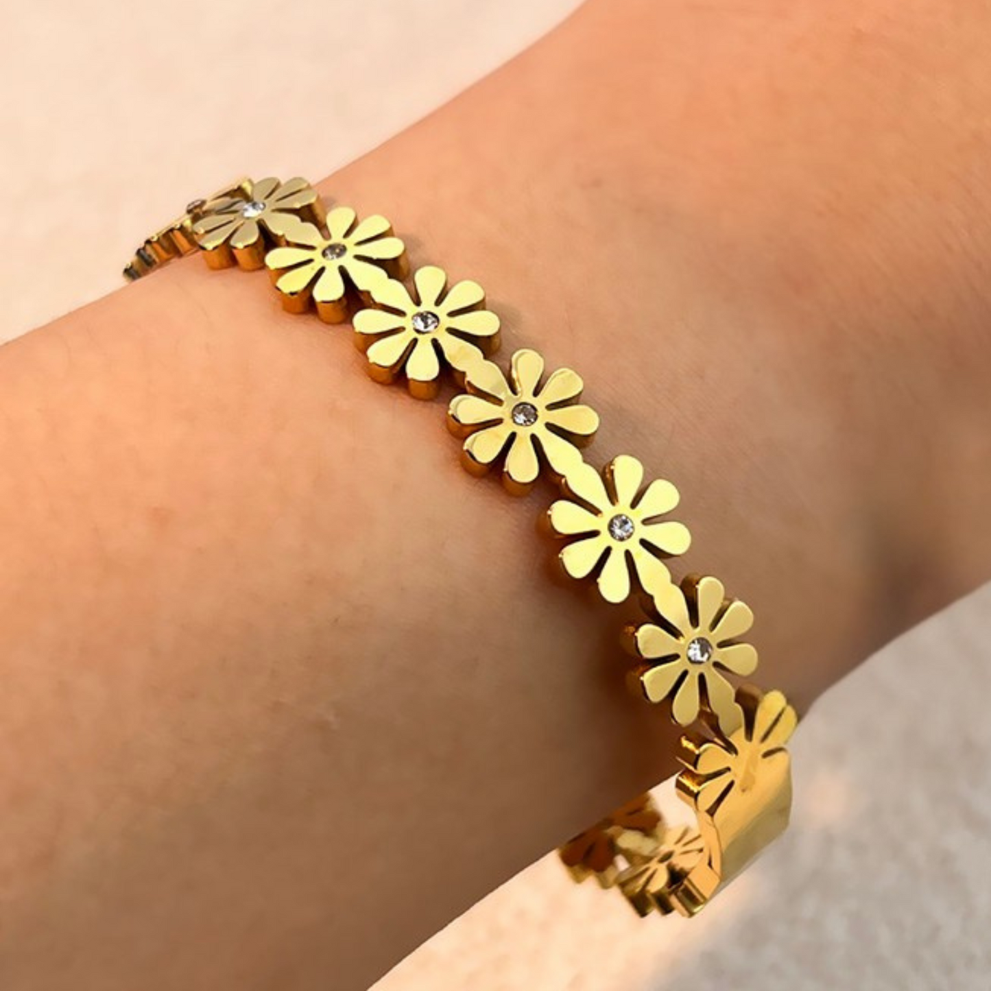 Gold floral bracelet on a wrist against a neutral background