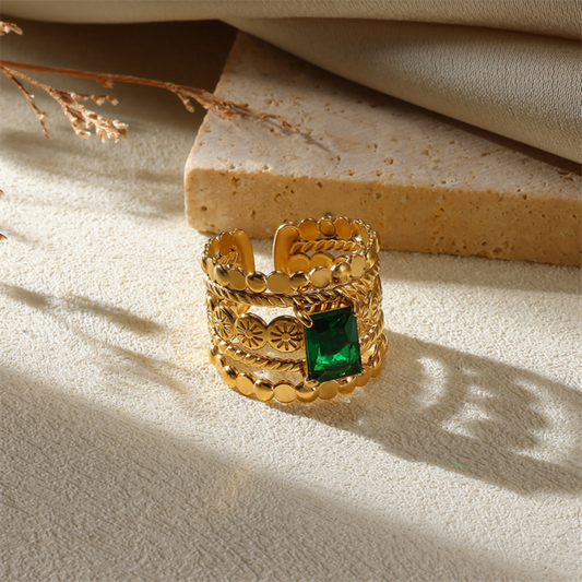 Gold ring with a green gemstone on a textured surface