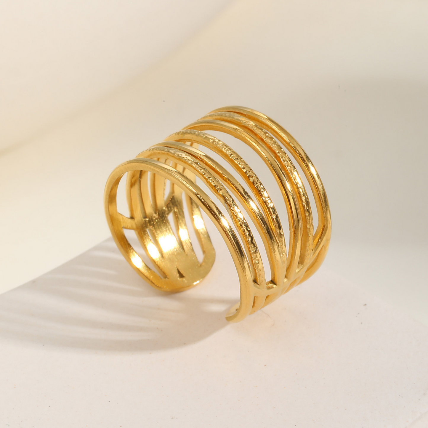 Gold ring with multiple loops on a beige background