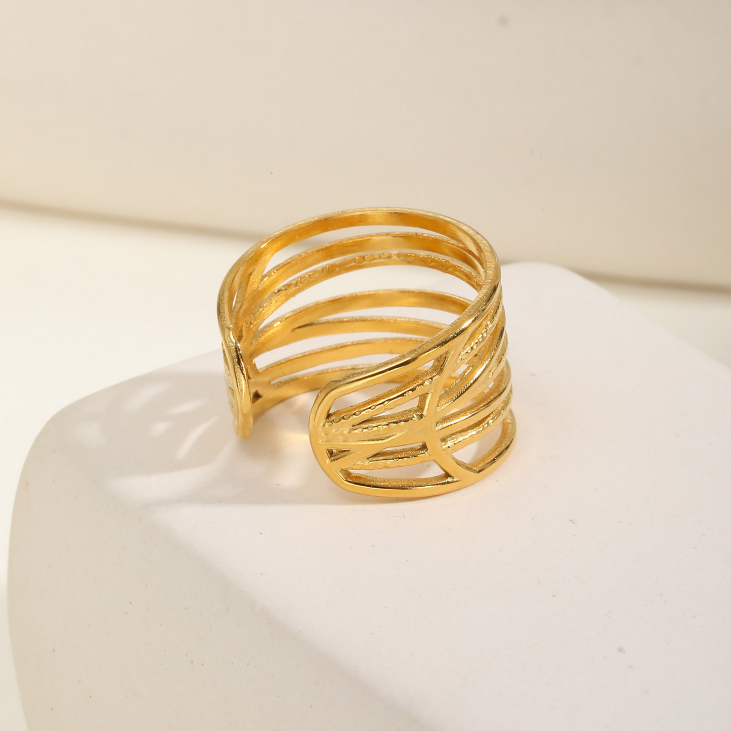 Gold ring on a white surface with a beige background