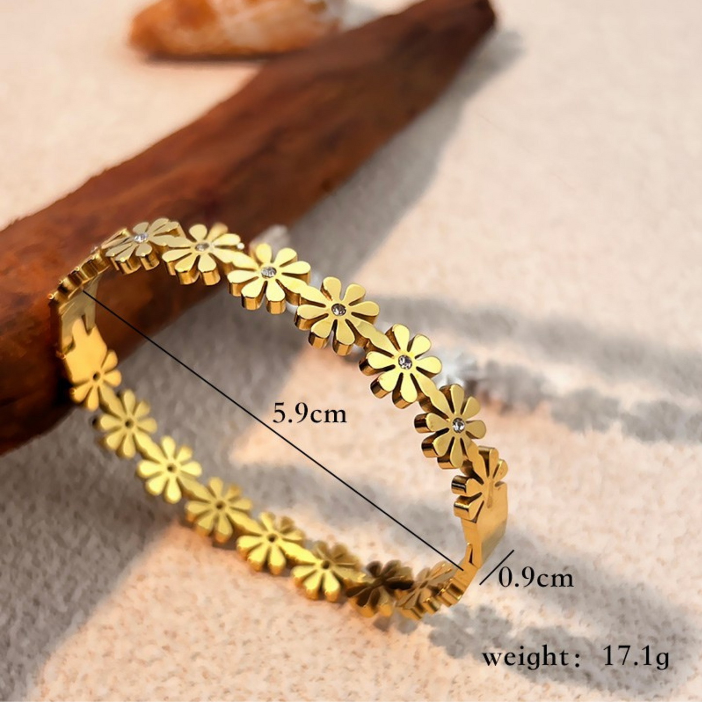 Gold bracelet with floral design on a textured surface