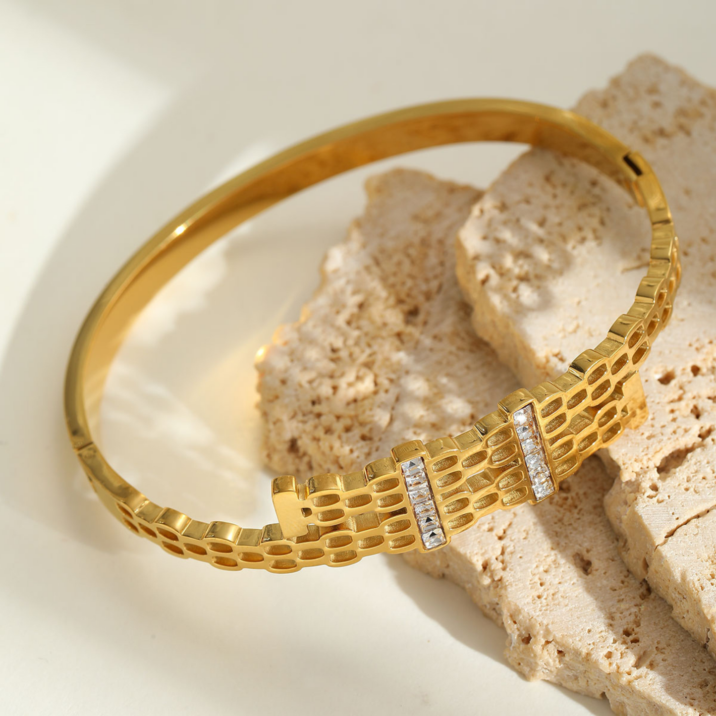 Gold bracelet with diamond accents on a textured beige surface