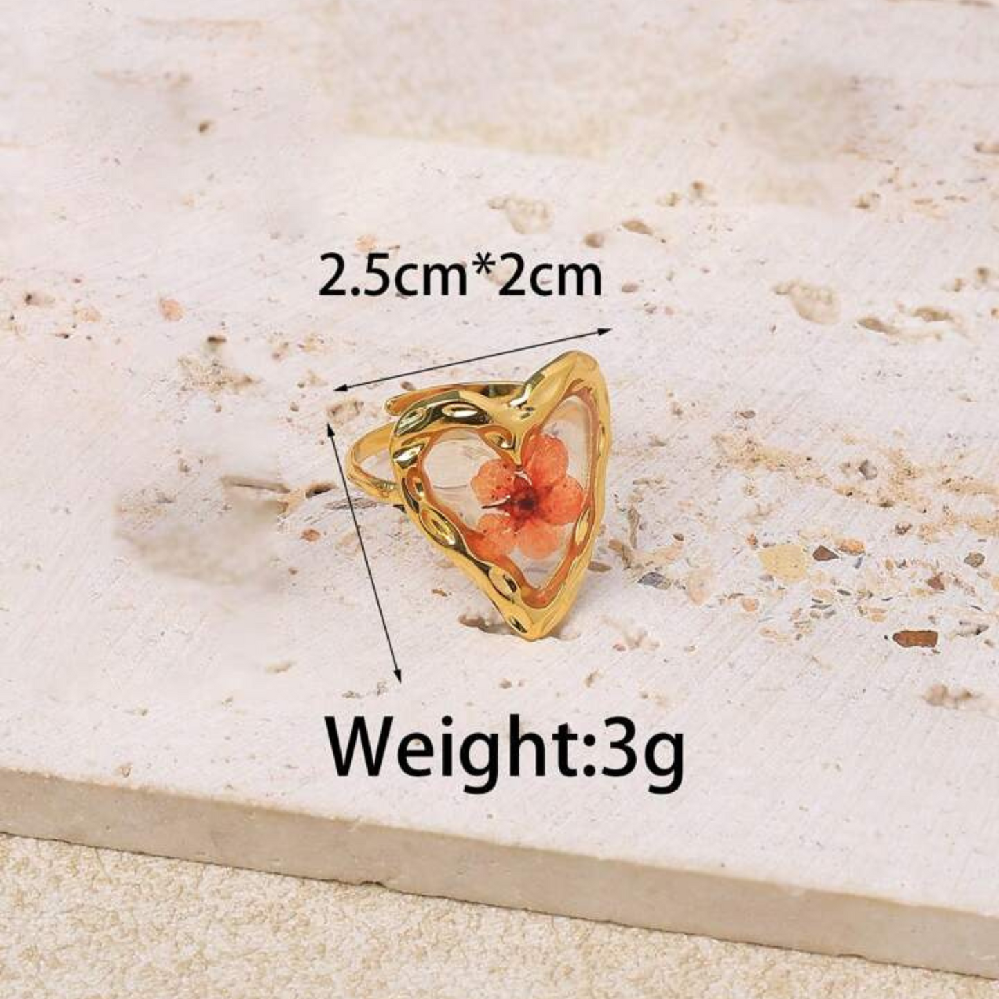 Gold ring with a floral design on a textured surface, showing measurements and weight.