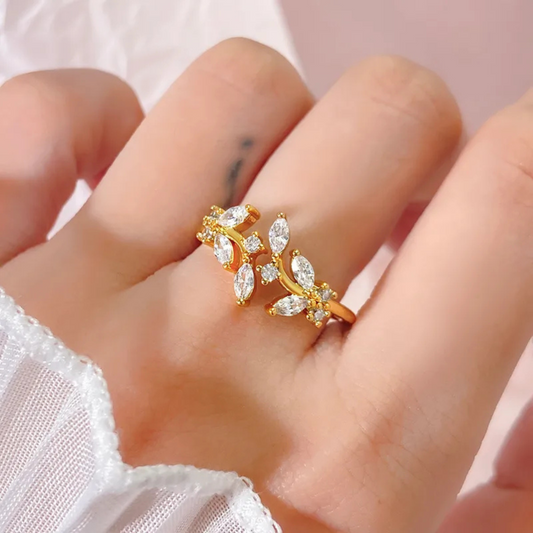 Gold ring with diamond-like stones on a finger against a light background