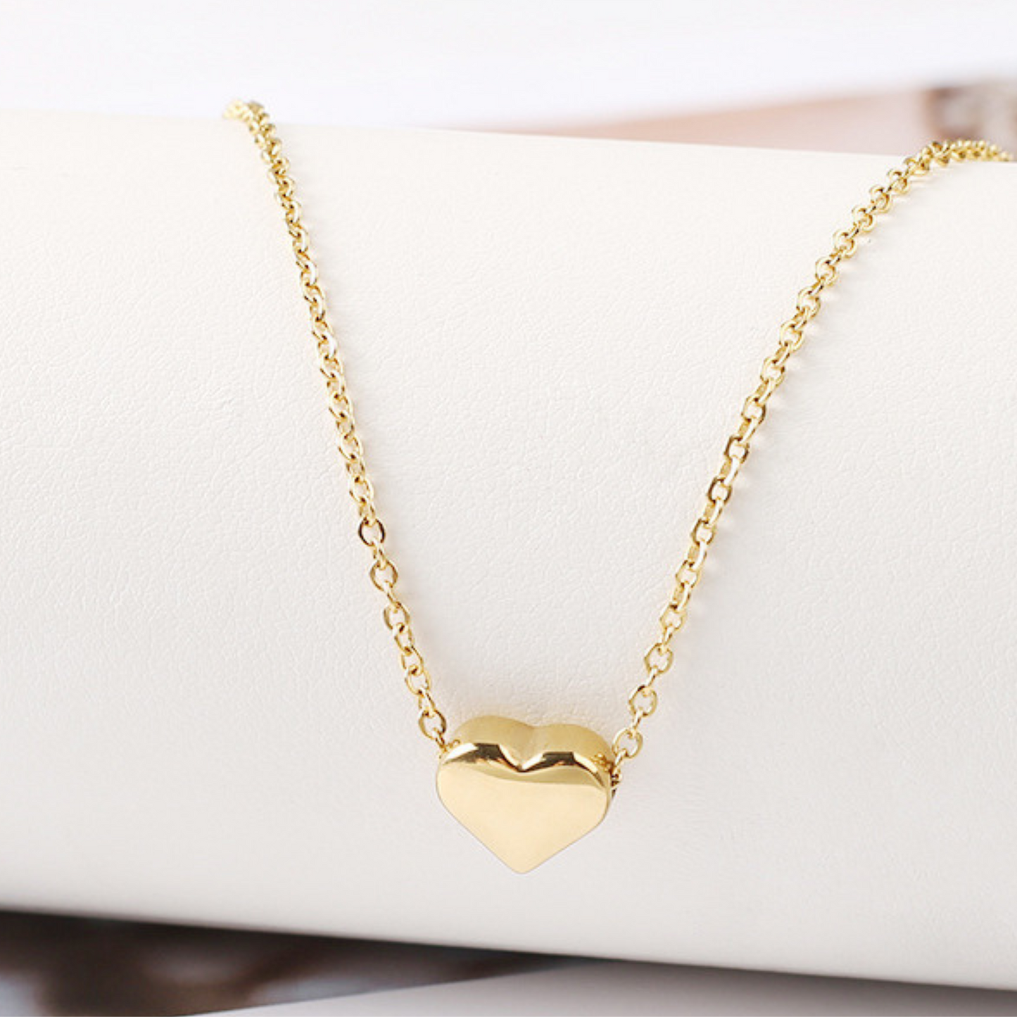 Gold heart-shaped necklace on a white surface