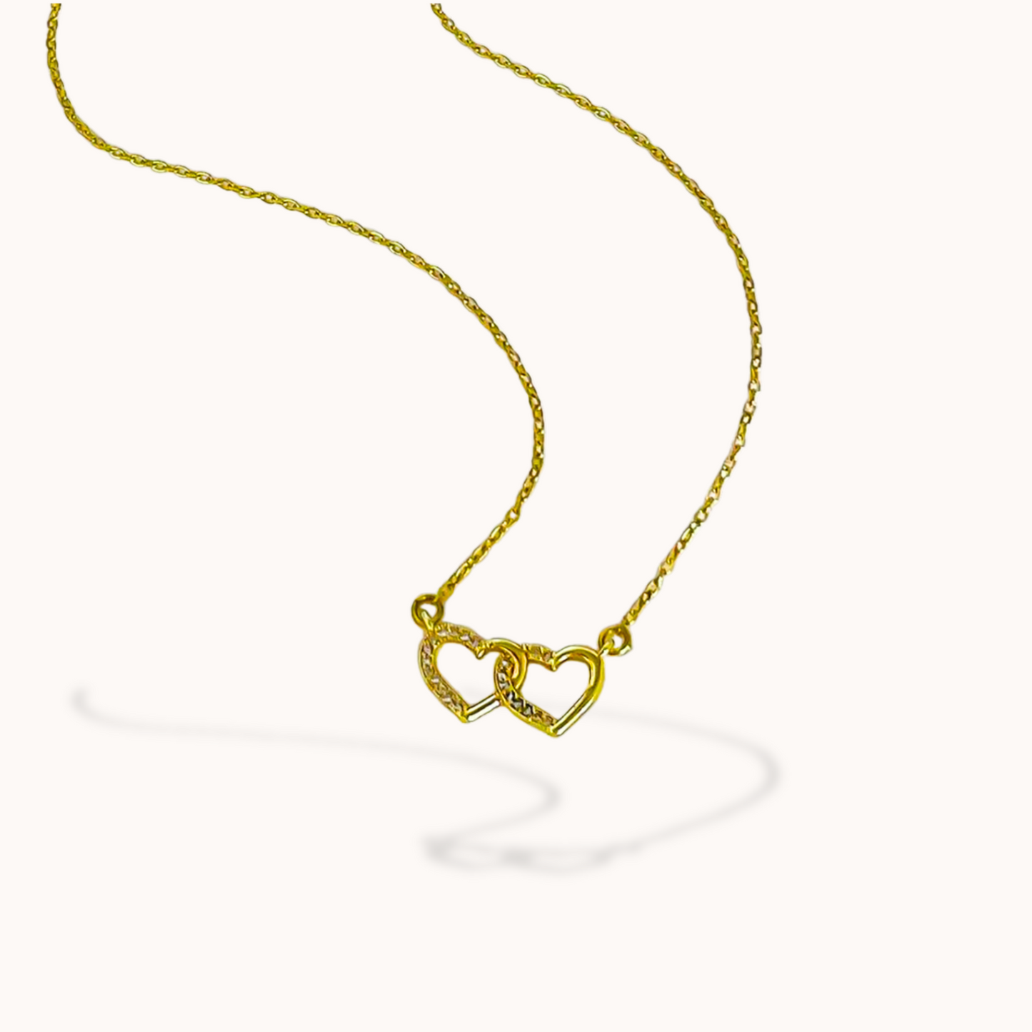 Gold necklace with a heart-shaped pendant on a white background