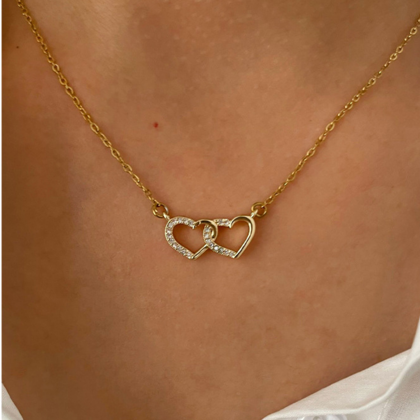Gold necklace with interlocking heart pendants on a person's neck