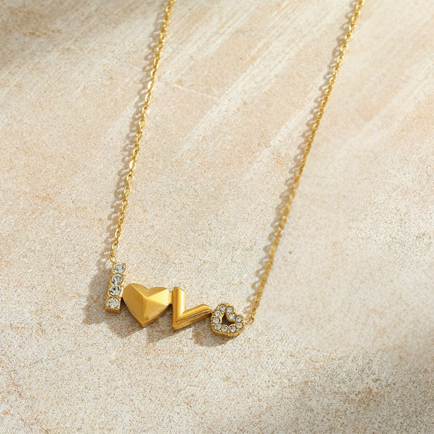 Gold necklace with heart-shaped pendants on a beige surface