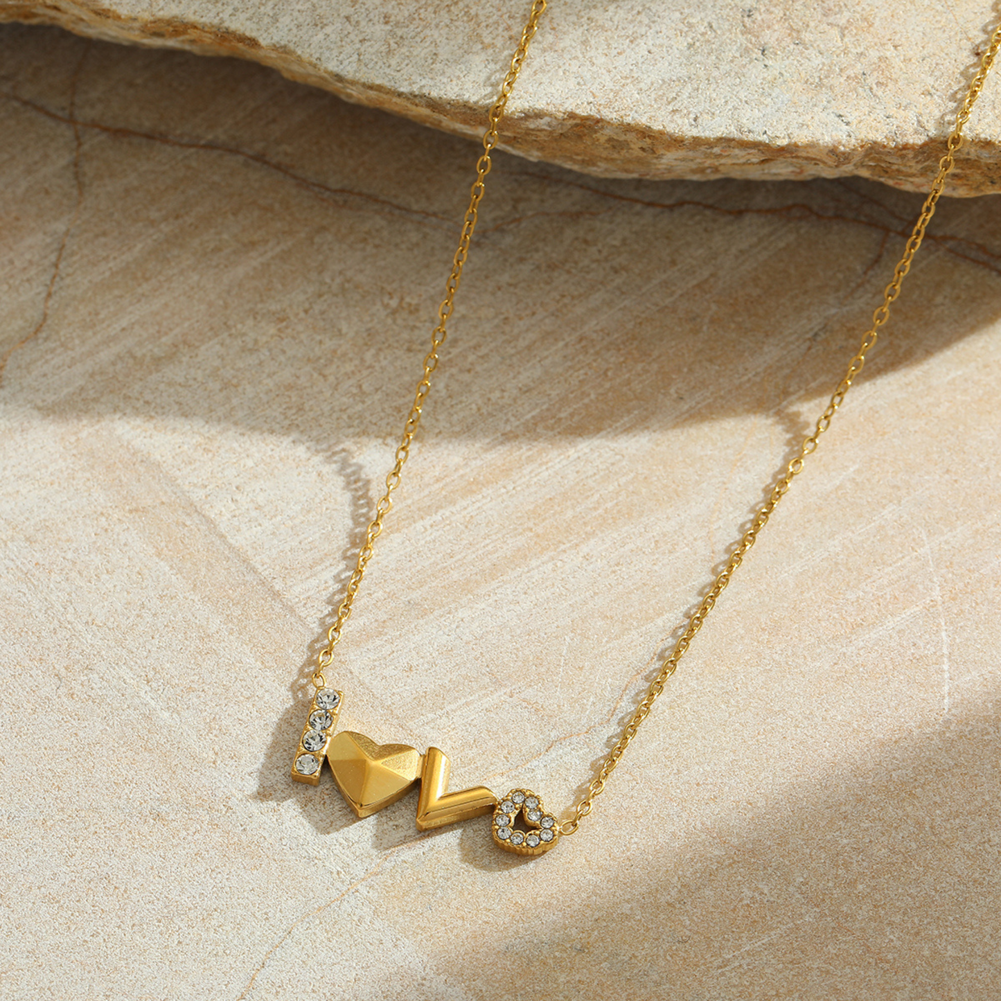 Gold necklace with heart-shaped pendants on a stone surface