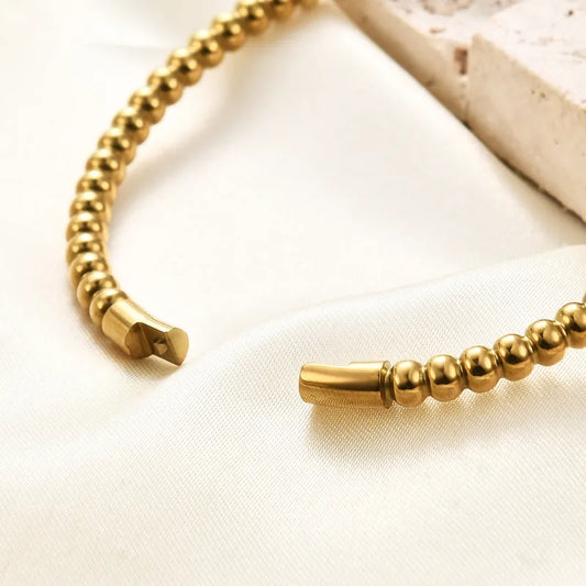 Gold beaded bracelet on a light fabric background