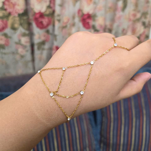 Gold chain bracelet on a wrist with a floral background