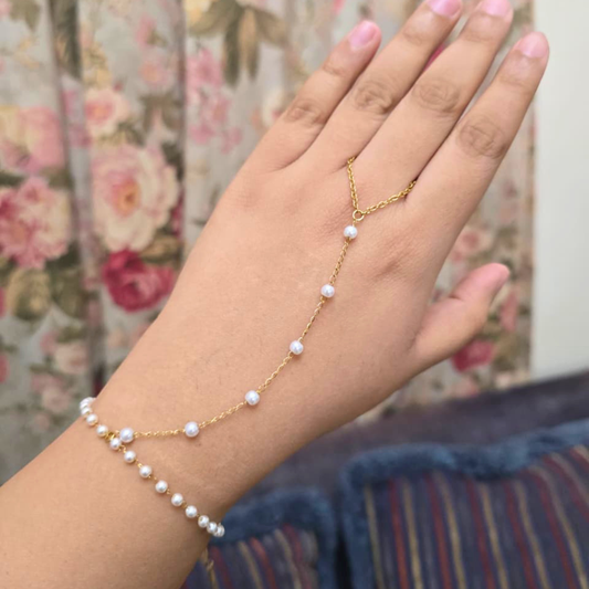Gold chain with pearls on a hand against a floral background