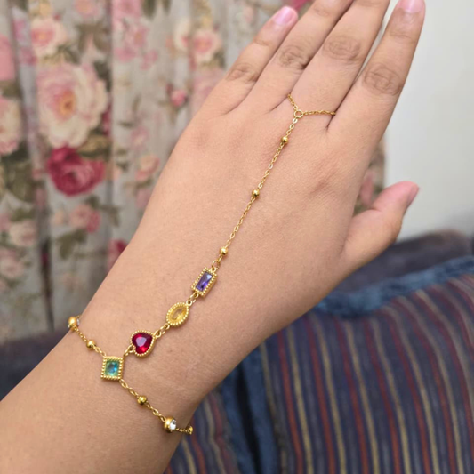 Gold bracelet with colorful gemstones on a hand against a floral background