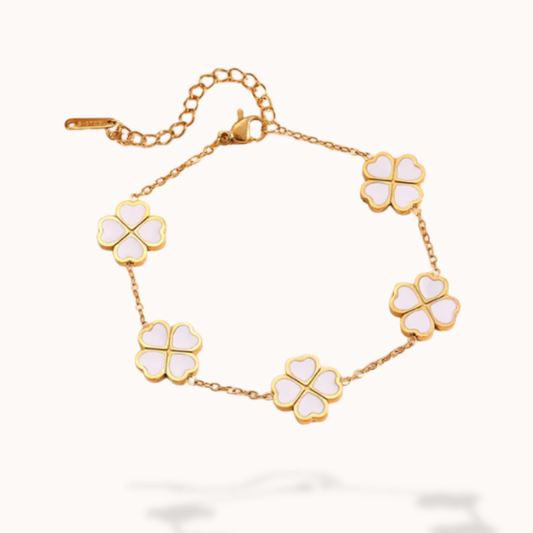 Gold bracelet with white four-leaf clover charms on a white background