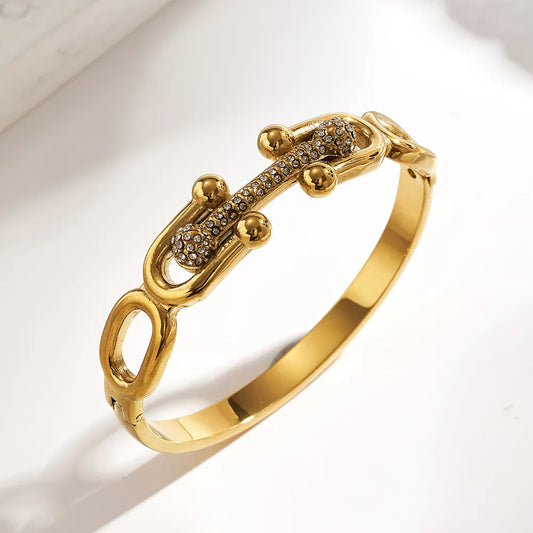 Gold bracelet with intricate design on a light background