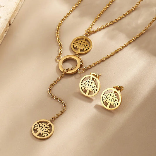 Gold necklace with tree-shaped pendants on a beige surface