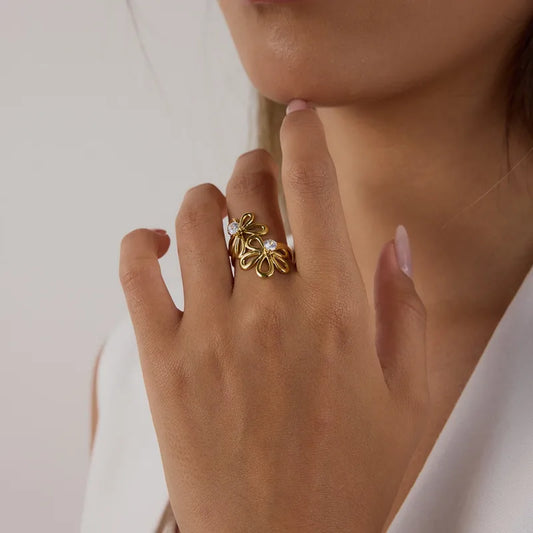 Close-up of a hand wearing a gold ring with a diamond on a neutral background