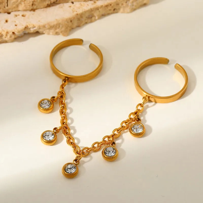 Gold hoop rings with chain and gemstones on a beige background
