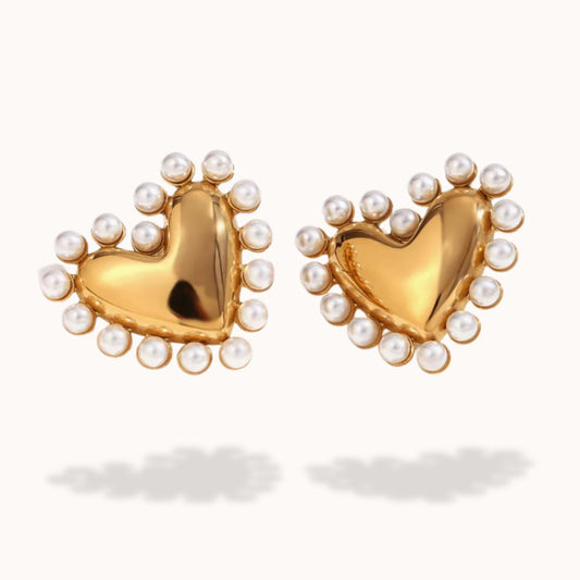 Gold heart-shaped earrings with pearl accents on a white background