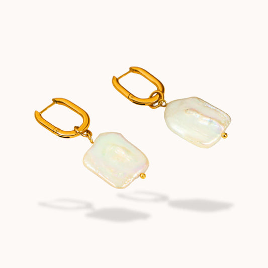 Gold earrings with dangling Fresh water pearl on a white background