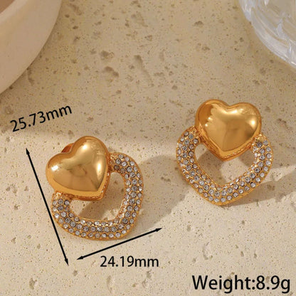 Gold heart-shaped earrings with measurements and weight on a beige surface